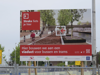 907291 Afbeelding van het bouwbord 'Hier bouwen we aan een viaduct voor bussen en trams', op het Westplein bij de Van ...